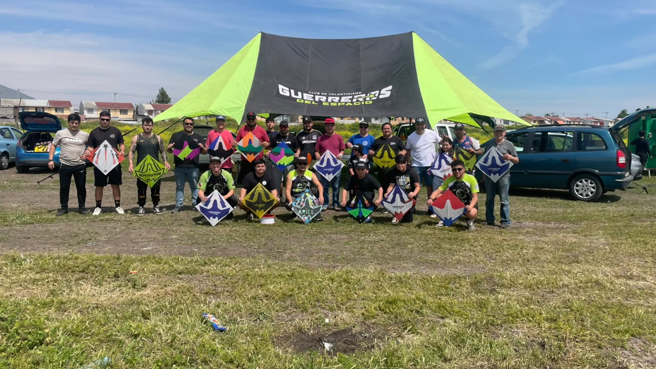 Foto grupal del equipo con volantines frente a la carpa del club durante el día